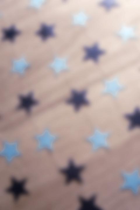 Defocused soft star background for Christmas with scattered light and dark blue stars on wood in a high angle full frame view