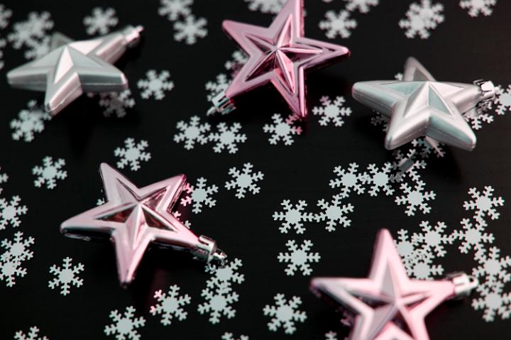Pink stars and snowflakes randomly scattered across black for your Christmas background