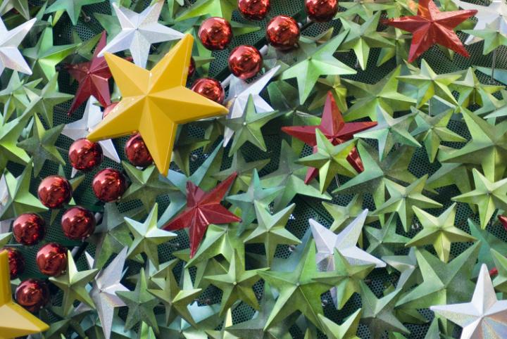 A background of festive metallic stars and red baubles