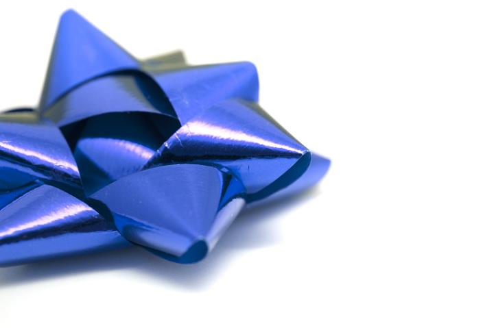 Metallic blue ribbon bow for a gift on a white background with copy space for your message or seasonal greeting