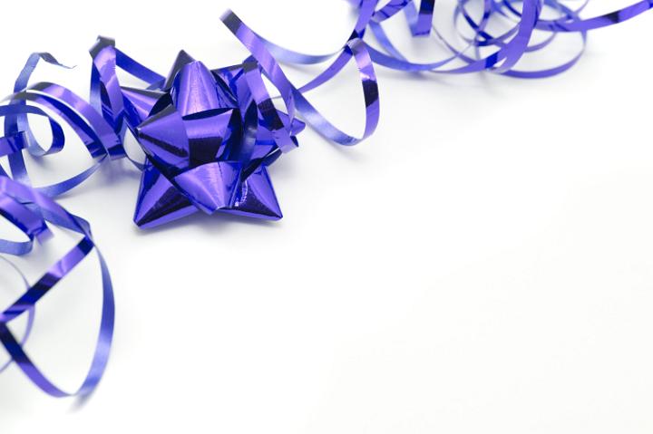 Purple festive corner border on a white background with copy space with a twirled party ribbon and decorative bow