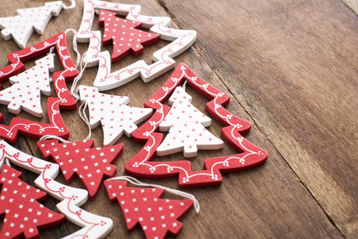 Assorted red and white wooden tree ornaments for celebrating Christmas forming a side border on a wood table with copy space