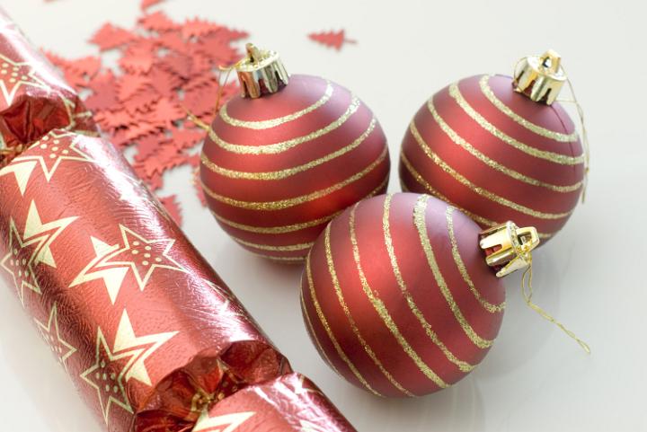 a selection of red coloured christmas balls, crackers and confetti glitter