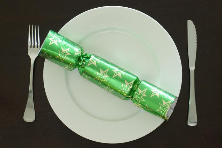 a plate set at a christmas dinner table, knife, fork and a festive cracker