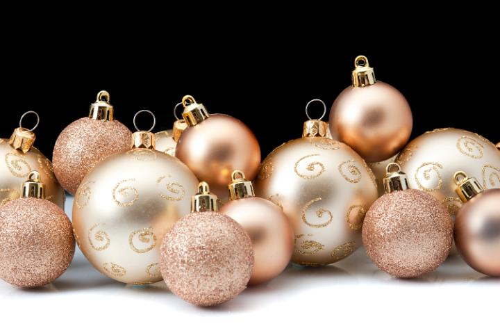 an arrangement of gold coloured christmas baubles with a back background and white foreground