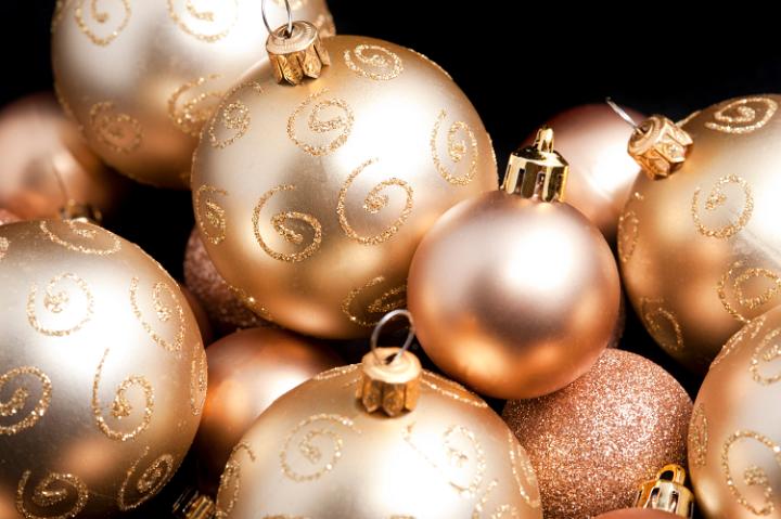 Festive background with random golden Christmas balls of different sizes, textures and patterns on a dark background