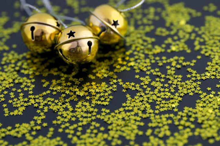 Golden Christams sleigh bells surrounded by scattered gold stars forming a copyspace for your seasonal greetings