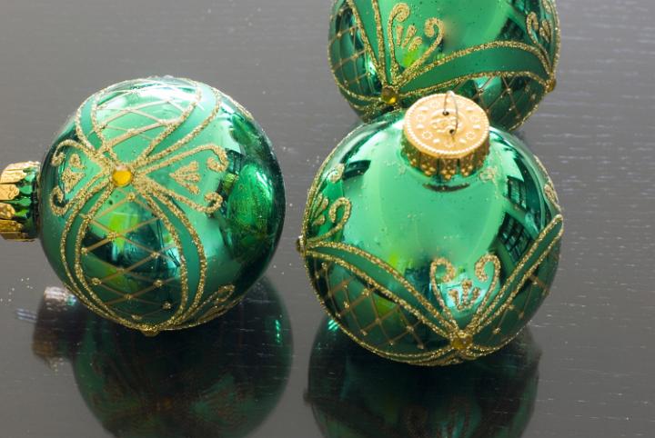 Three green reflective glass bauble decorations on a dark background
