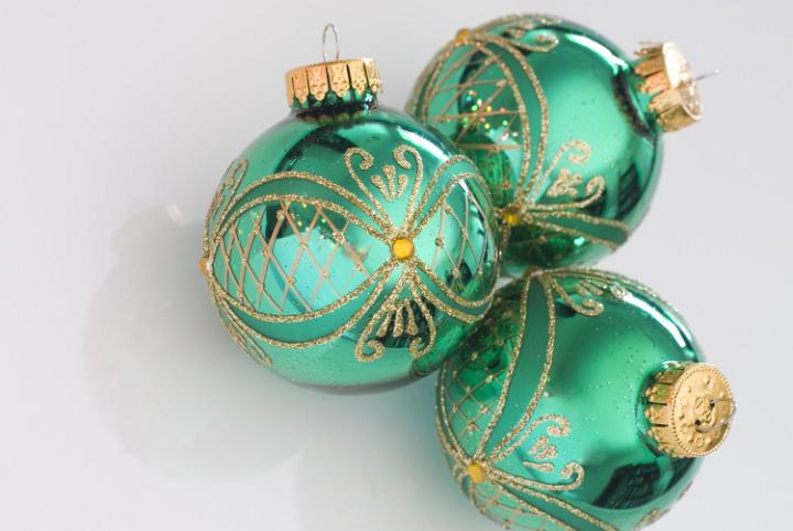 Three green glass christmas ornaments on a plain white background