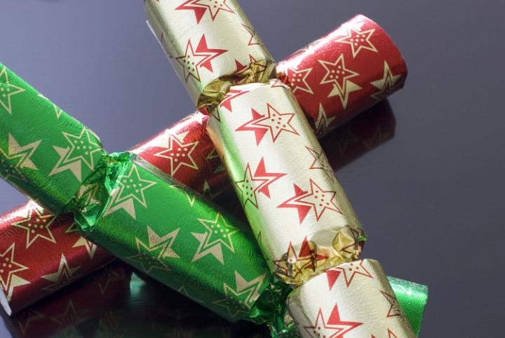 Three different coloured chrismas crackers on a dark polished background