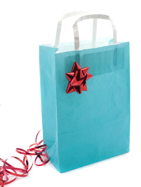 Pretty pastel blue Christmas shopping bag decorated with an ornamental red bow and twirled ribbon on a white background