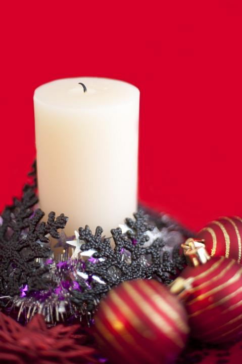 an arrangement of an unlit christmas candle surrounded with various sparkling christmas decorations