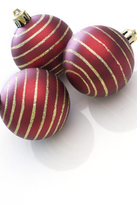 a trio of red christmas tree baubles with gold glitter stripes