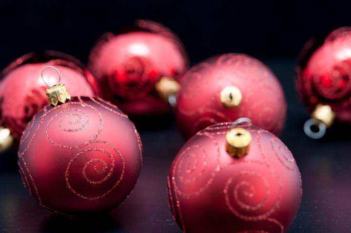 Closeup of red decorative Christmas baubles with glitter pattern on a black background