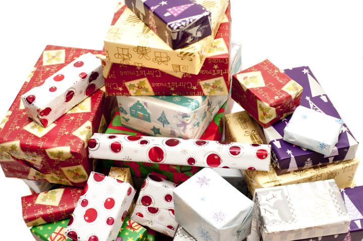 Large pile of multicolored Christmas gifts in decorative seasonal wrapping paper in a close up background view over white