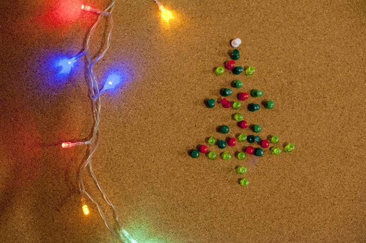 Close-up of lighted garland and handmade Christmas tree made of colorful pins. From above
