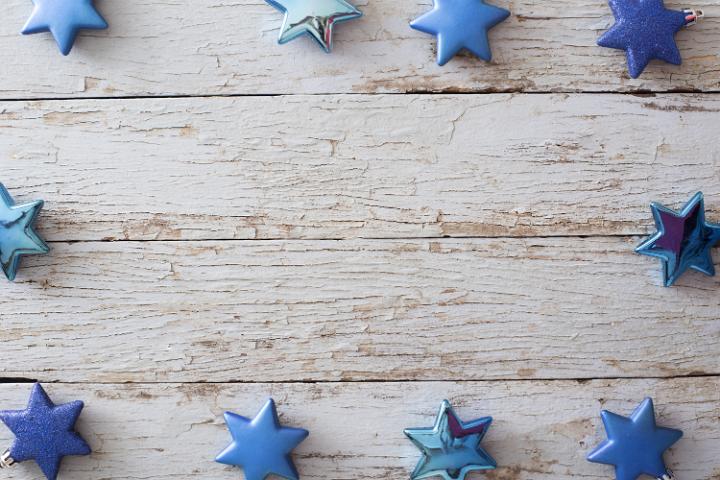 Decorative blue star Christmas border or frame on old rustic weathered textured wood around a central copy space for your holiday greeting