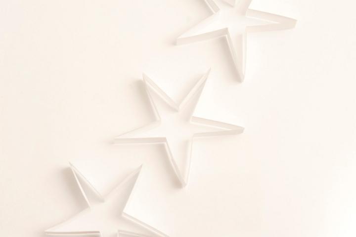 Simple white paper Christmas decorations with three stars in a diagonal row with copyspace