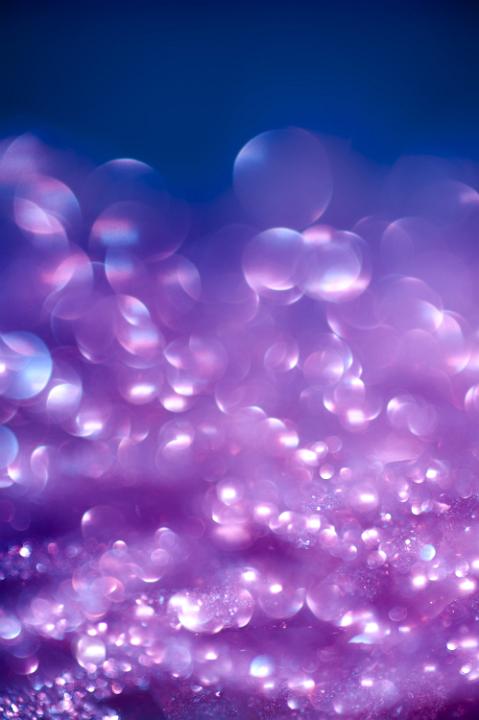 a background of defuse purple bokeh highlights and colorful glitter sparkles