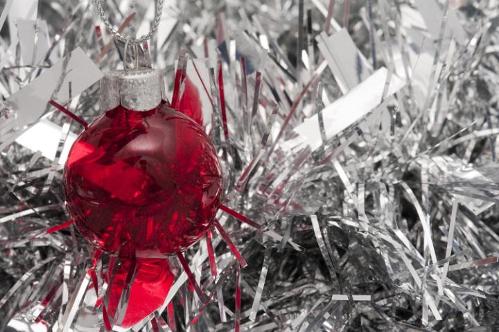 red christmas ornament on background of silver glittering tinsel
