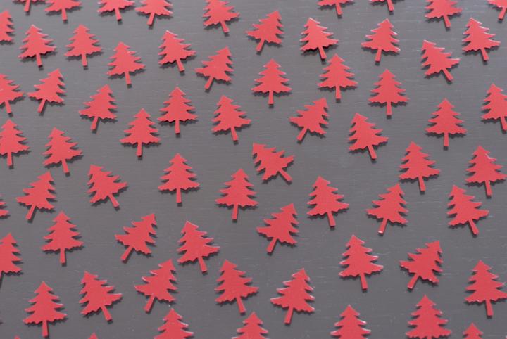 a background image of red christmas tree confetti arranged on a table top