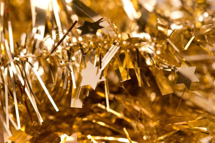 Glittering gold tinsel with little stars as a backdrop for your Christmas or festive greetings card or invitation