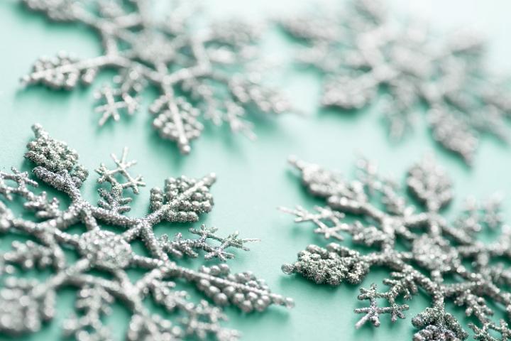 Green tinted glitter snowflakes Christmas background viewed at an oblique angle with shallow dof