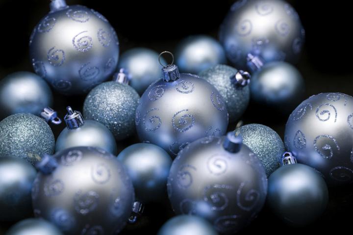 Group of decorative blue Christmas baubles some patterned, others with glitter texture on a dark background with selective focus to the centre