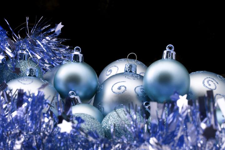 Blue Christmas tinsel and baubles on a black background with copyspace