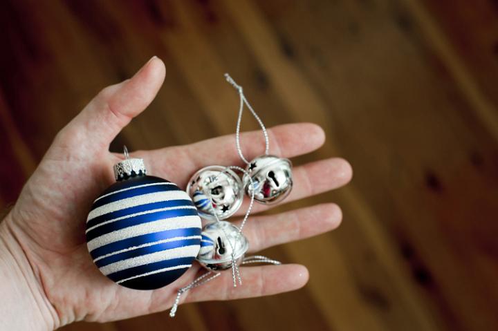 Close up shot of a hand with a blue bauble and some metallic closed bells