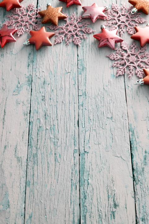 Rustic Christmas border of orange stars and snowflakes on blue textured weathered wood with copy space, oblique angle view