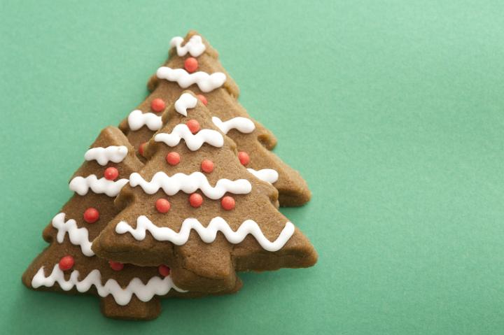 Decorative iced gingerbread Christmas tree cookies stacked on a green background with copy space for your seasonal greeting