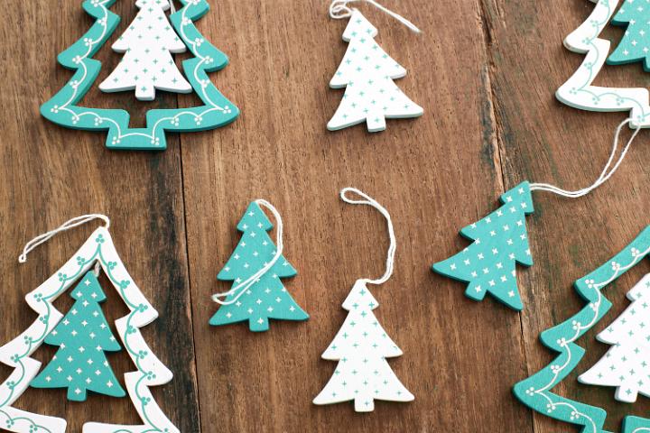 Decorative Christmas tree ornaments with cut out tree shapes with polka dot decoration lying on a wood background