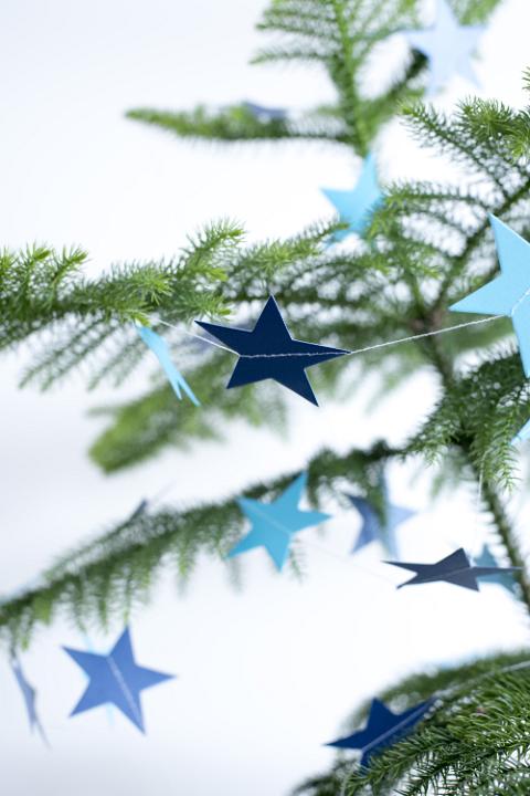 Simple natural evergreen pine Christmas tree with blue paper stars for a country celebration of the holiday season