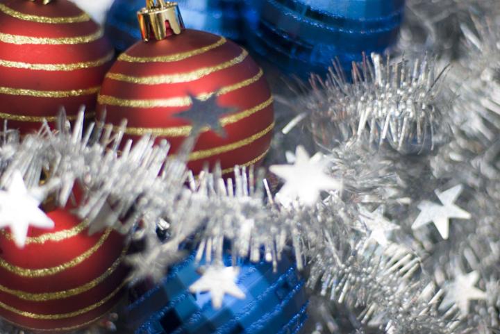 blue and red festive baubles on a background of tinsel, pictured with a narrow depth of field
