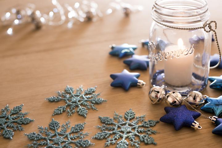 Still life of some decorative snowflakes and a jar with a lit candle inside