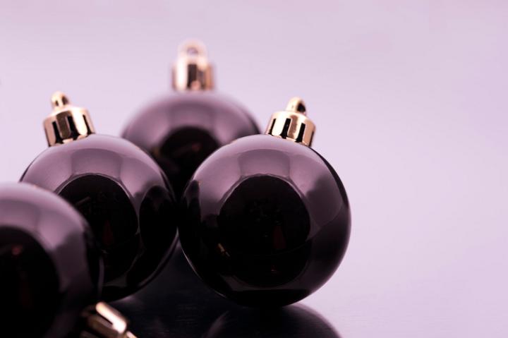 Black Christmas balls with reflections on a grey toned studio background with copyspace for your Xmas message