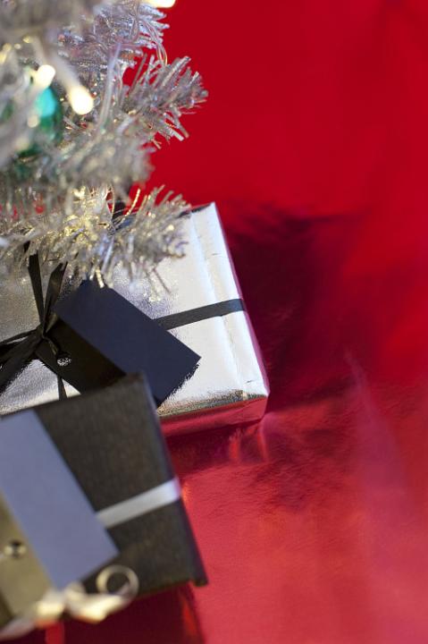 a background image with space for text featuring a silver christmas tree and presents at an oblique angle