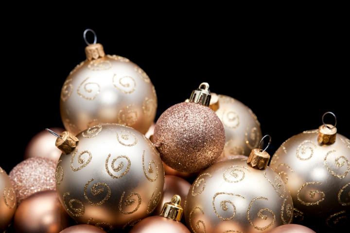 a black background with copyspace framed with a selection of glittery gold christmas ornaments