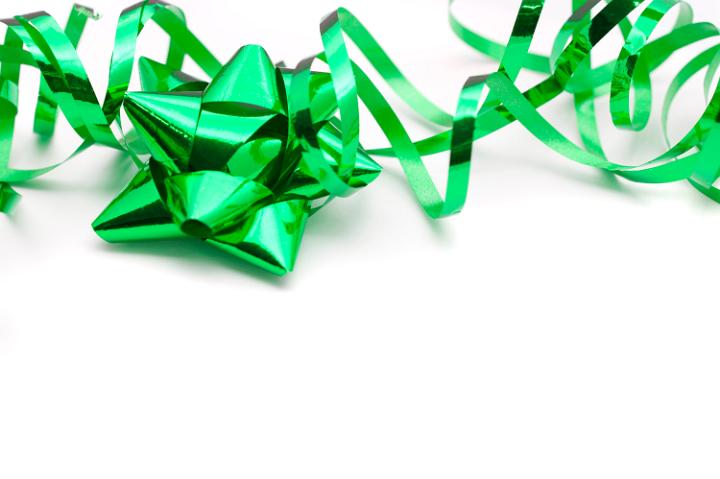 Festive metallic green bow and twirled ribbon for gift wrapping Christmas gifts or presents for a special occasion on a white background with copyspace