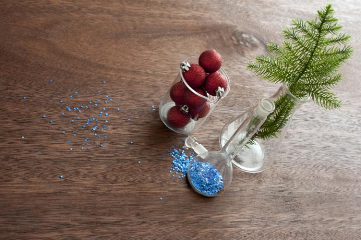 Christmas decoration, blue sparkles and fir branch on wooden table in glass containers, making christmas concept