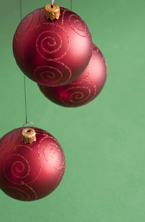 Three Christmas balls hanging on green background