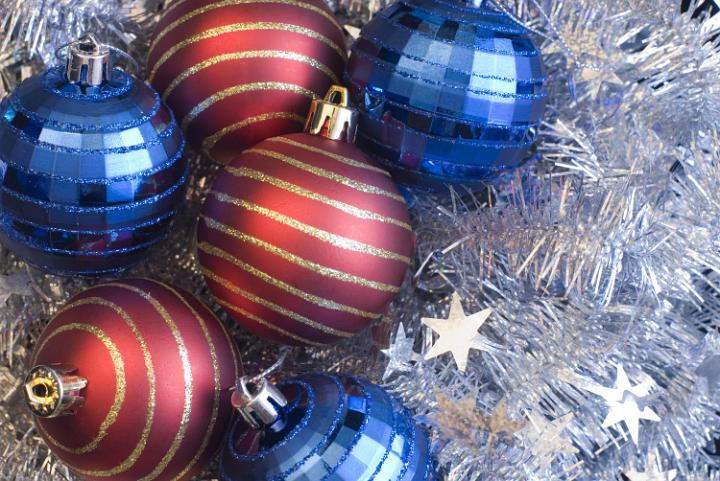 blue and red festive baubles on a background of silver tinsel