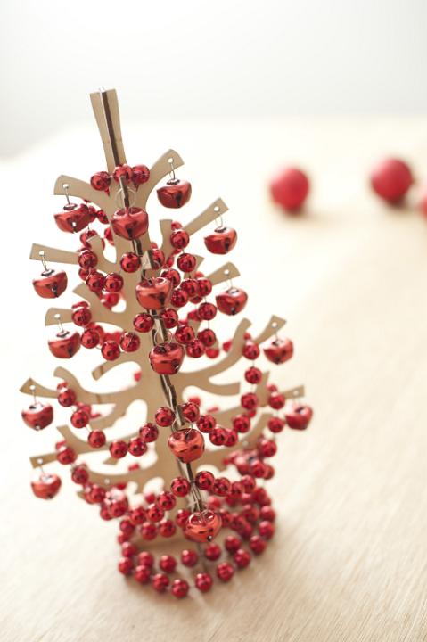 Close-up of wooden Christmas tree decorated with red garland and Christmas balls. Daylight