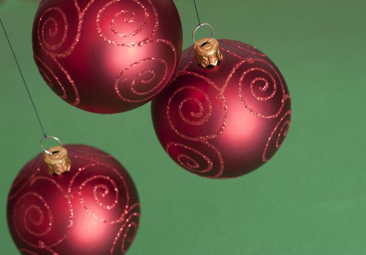 Close-up of three red Christmas balls hanging against of green background