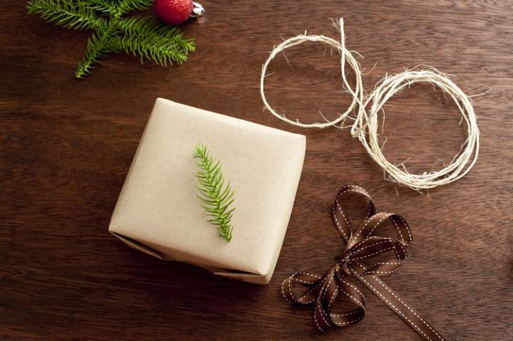 Wrapped Christmas present, brown decorative ribbon, rope and branch of fir tree. From above