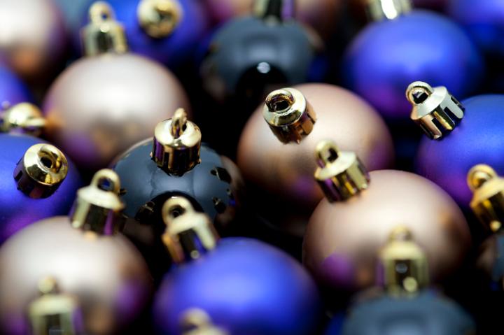 close up image of an array of small plain chirstmas bauble tree ornaments, metallic purple, gold and black in colour