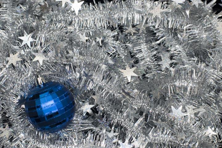 a bed of silver tinsel with a blue christmas bauble