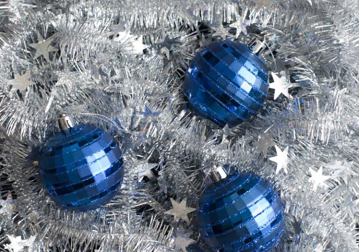 a bed of silver tinsel with three blue christmas baubles