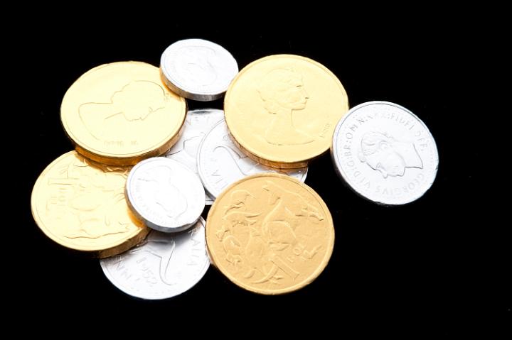 Gold and silver candy coins made of foil wrapped chocolate for a party celebration or kids treat on a black background